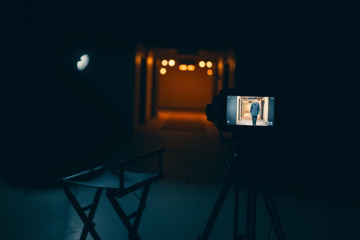A cinema camera and director's chair on a dark set, monitor glowing